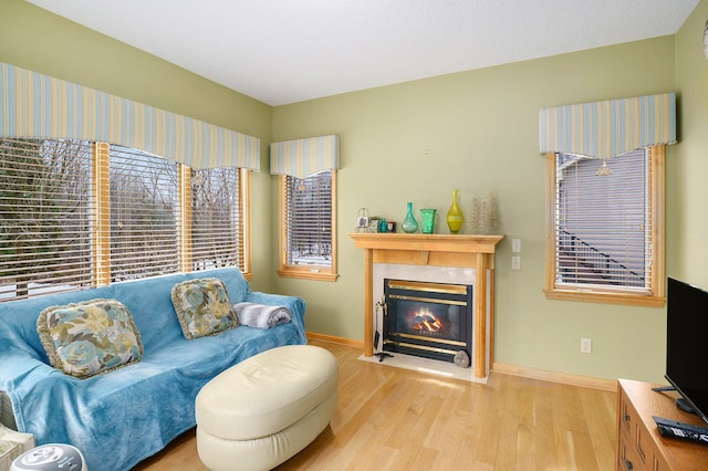 living room featuring a fireplace with flush hearth, light wood-type flooring, and baseboards