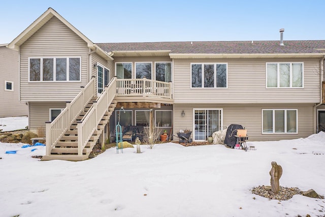 snow covered back of property featuring stairway