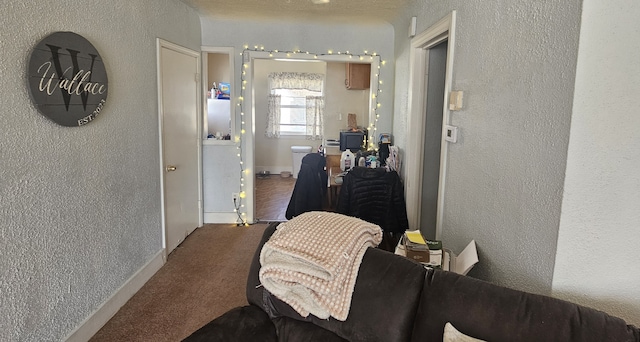 hallway featuring carpet floors, a textured wall, and baseboards