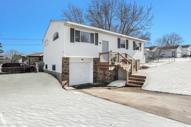 raised ranch with an attached garage, concrete driveway, and brick siding