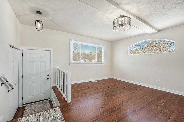 entrance foyer with dark wood-style floors, a notable chandelier, baseboards, and a textured ceiling