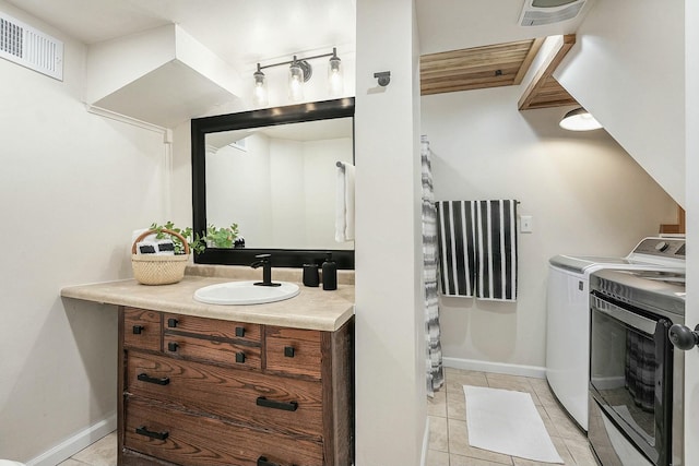 bathroom featuring tile patterned flooring, visible vents, washer and clothes dryer, and vanity