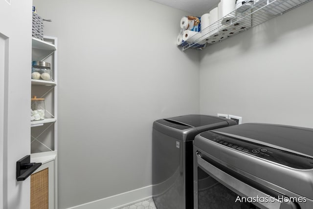 laundry room featuring laundry area, washing machine and dryer, and baseboards