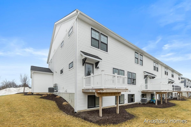 rear view of property with a deck, cooling unit, and a yard