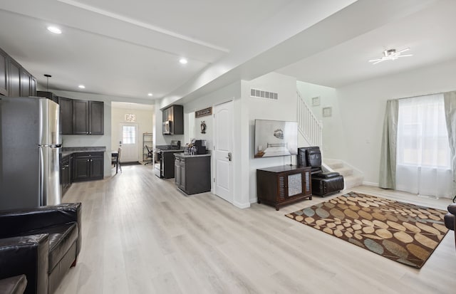 living area featuring light wood-style floors, recessed lighting, visible vents, and stairs