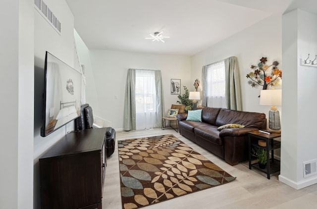 living room featuring visible vents, light wood-style flooring, and baseboards