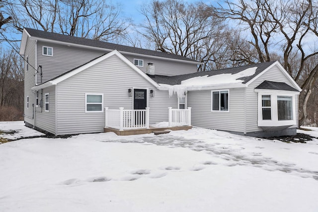 snow covered rear of property with a wooden deck