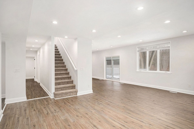 interior space featuring baseboards, stairway, wood finished floors, and recessed lighting