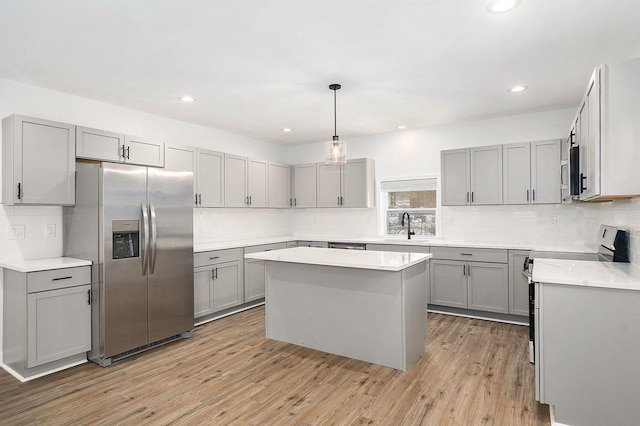 kitchen with light wood-type flooring, appliances with stainless steel finishes, and gray cabinets