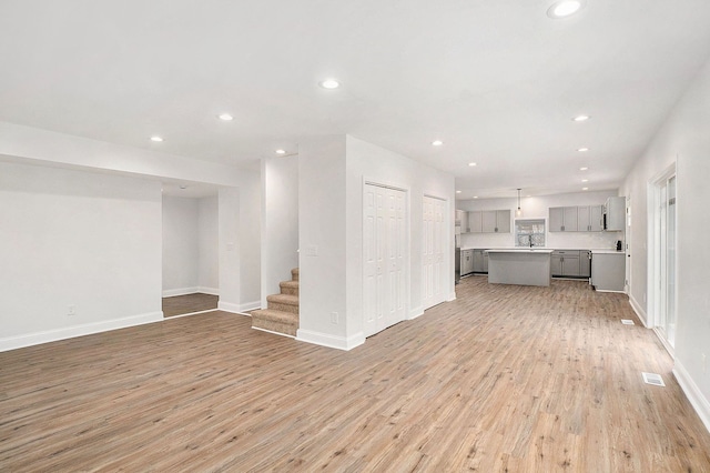 unfurnished living room featuring recessed lighting, visible vents, stairway, light wood-style floors, and baseboards