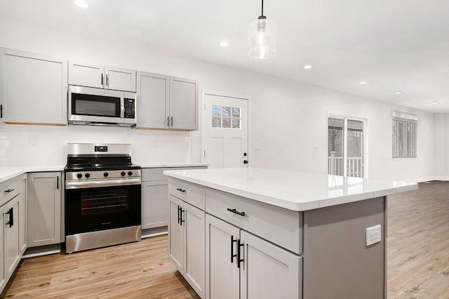 kitchen with tasteful backsplash, appliances with stainless steel finishes, light wood-type flooring, and gray cabinetry