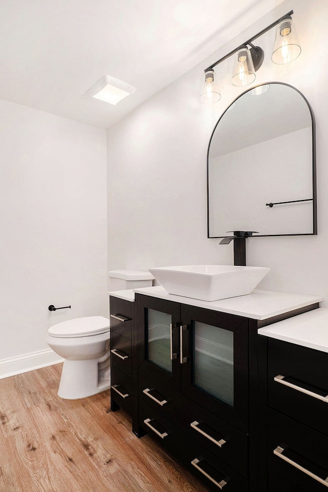 bathroom featuring toilet, baseboards, wood finished floors, and vanity