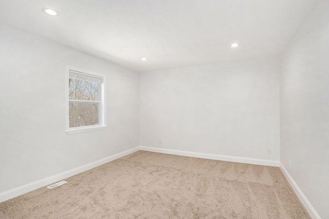 spare room with baseboards, recessed lighting, visible vents, and light colored carpet