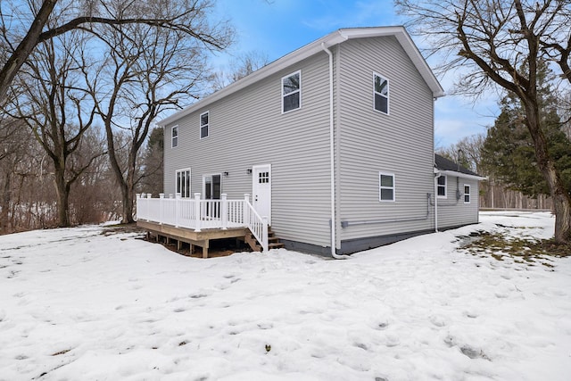 snow covered back of property with a deck