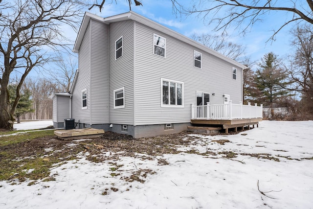 snow covered rear of property featuring central AC unit and a wooden deck