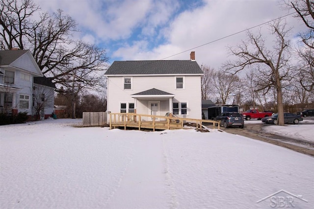 snow covered back of property with a chimney and a wooden deck