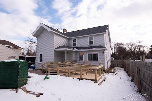 view of front of house with a chimney, fence, and a wooden deck