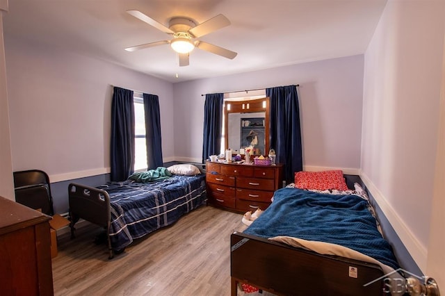 bedroom featuring ceiling fan, light wood-style flooring, and baseboards