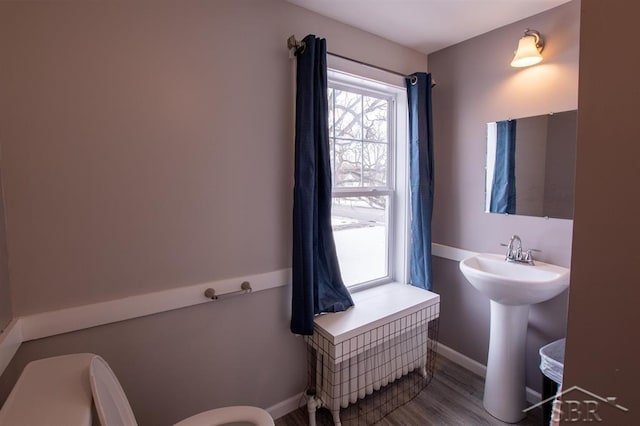 bathroom featuring baseboards, a sink, toilet, and wood finished floors