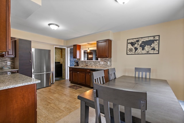 kitchen with backsplash, a sink, freestanding refrigerator, and light wood-style floors