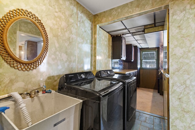 laundry area featuring washing machine and clothes dryer, ornamental molding, stone finish floor, a sink, and laundry area