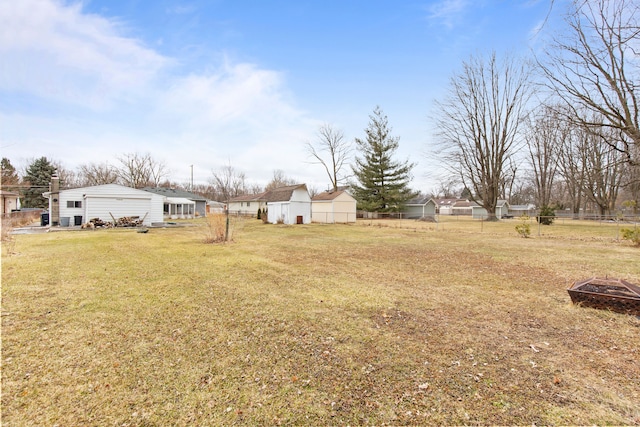 view of yard featuring an outbuilding, fence, and a fire pit