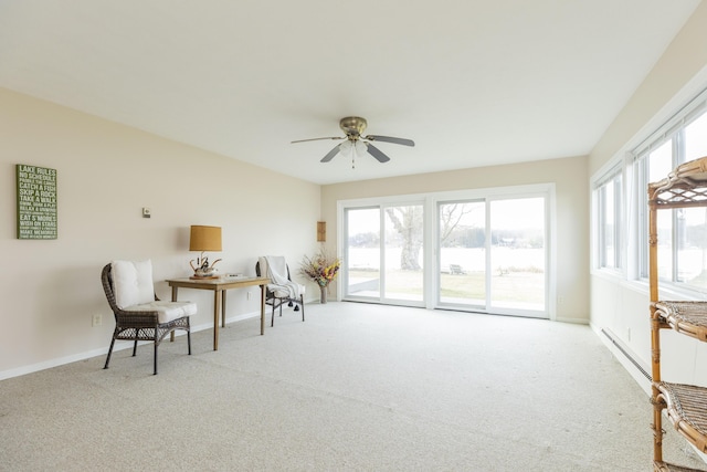 living area with baseboards, a baseboard heating unit, a wealth of natural light, and light colored carpet