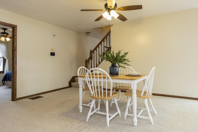 carpeted dining area featuring visible vents, stairs, baseboards, and a ceiling fan