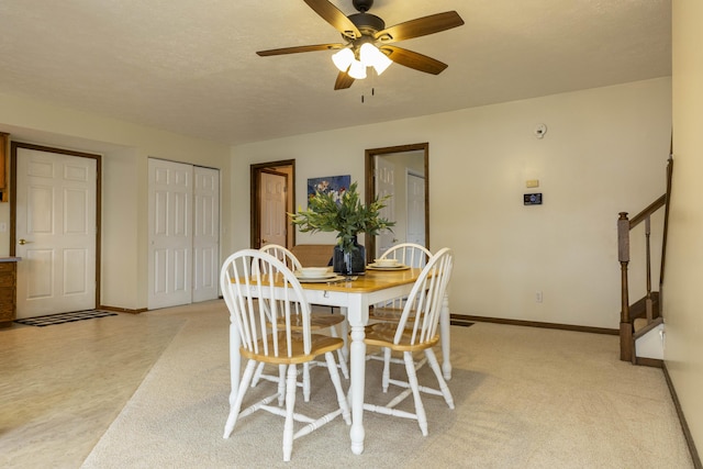 dining area featuring stairs, ceiling fan, a textured ceiling, and baseboards