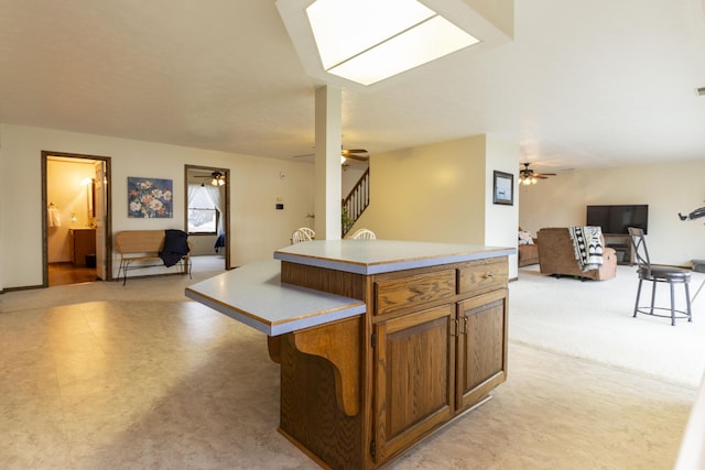 kitchen with brown cabinets, a kitchen island, open floor plan, and light countertops