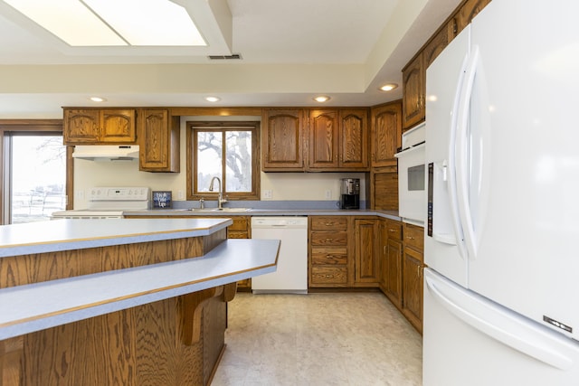 kitchen featuring white appliances, a sink, visible vents, and brown cabinets