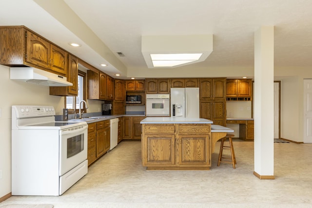 kitchen with brown cabinetry, a center island, white appliances, and a sink