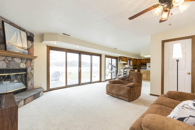 living area featuring light colored carpet, a fireplace, and visible vents