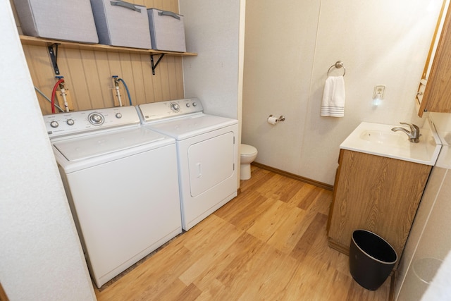 washroom with light wood-type flooring, laundry area, a sink, and independent washer and dryer