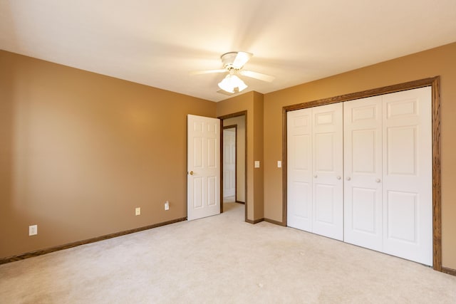 unfurnished bedroom with light carpet, a closet, a ceiling fan, and baseboards