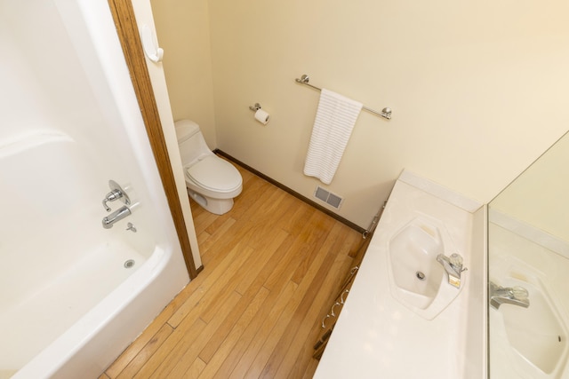 full bathroom featuring toilet, a sink, wood finished floors, visible vents, and baseboards