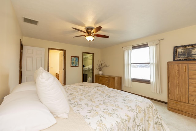 bedroom with visible vents, a spacious closet, light carpet, ensuite bath, and baseboards