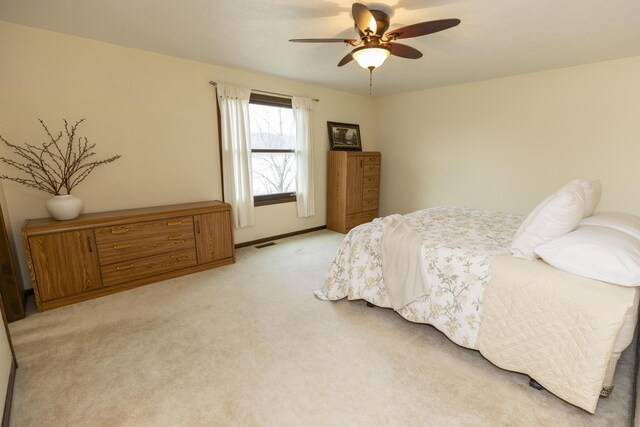 bedroom featuring a ceiling fan, light colored carpet, visible vents, and baseboards