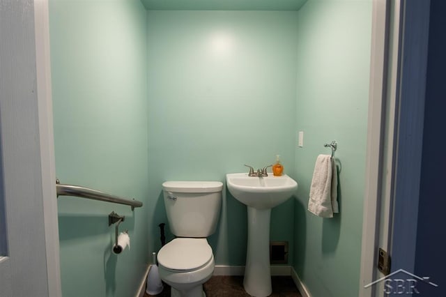 half bath featuring baseboards, a sink, and toilet