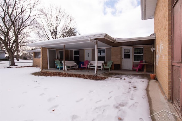 snow covered rear of property with brick siding