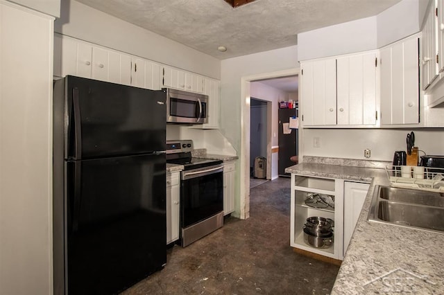 kitchen featuring light countertops, appliances with stainless steel finishes, white cabinets, a sink, and concrete floors