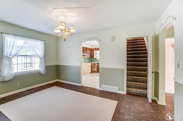 unfurnished room featuring arched walkways, stairs, and visible vents