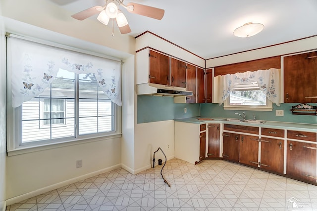 kitchen with light countertops, a healthy amount of sunlight, a sink, and under cabinet range hood