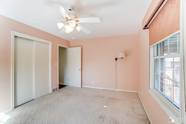 unfurnished bedroom featuring light carpet, baseboards, visible vents, ceiling fan, and a closet