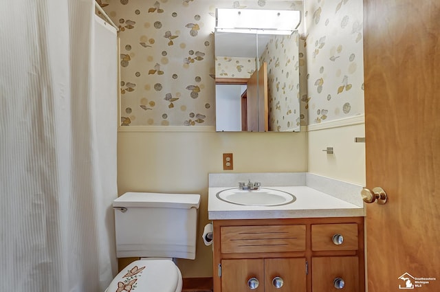 bathroom with toilet, wallpapered walls, and vanity