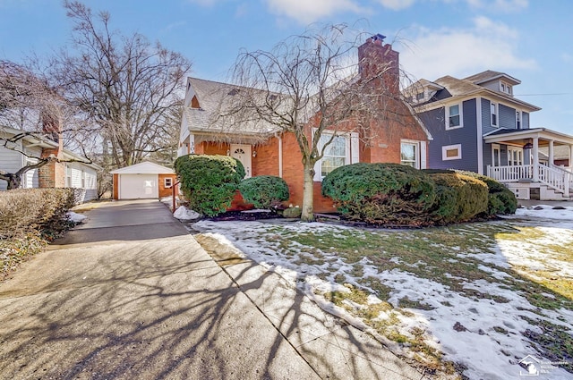 view of front of property featuring driveway, a detached garage, a porch, and an outdoor structure