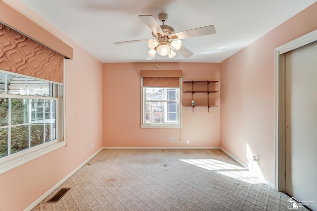 unfurnished room featuring light carpet, baseboards, visible vents, and ceiling fan