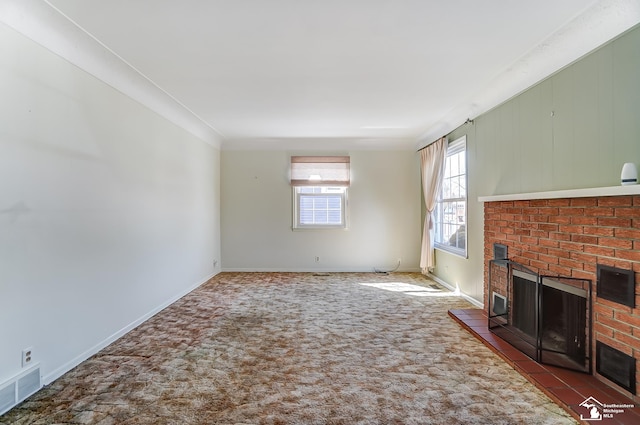 unfurnished living room with baseboards, a fireplace, visible vents, and dark carpet