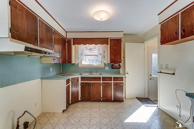 kitchen with light countertops, light floors, a sink, and under cabinet range hood