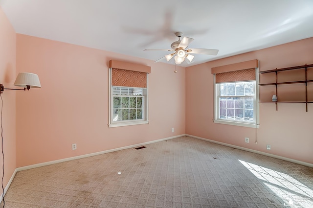 empty room featuring visible vents, a ceiling fan, and baseboards